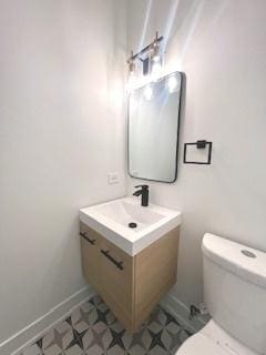 half bathroom featuring baseboards, vanity, and toilet