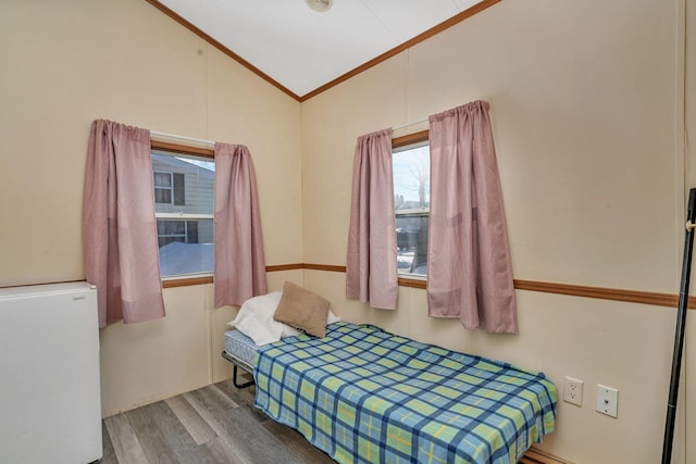 bedroom with ornamental molding, vaulted ceiling, and wood finished floors