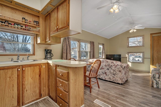 kitchen with a peninsula, brown cabinetry, light countertops, and a sink