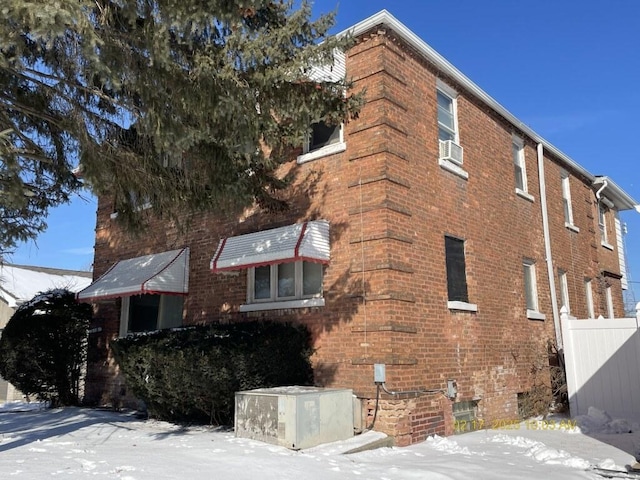 view of snowy exterior featuring brick siding