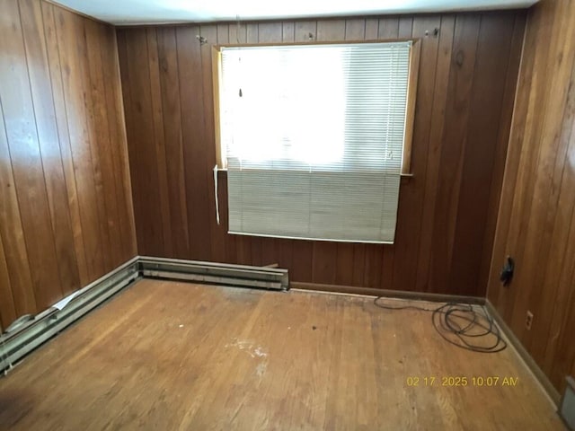 empty room featuring wooden walls, baseboards, and wood finished floors