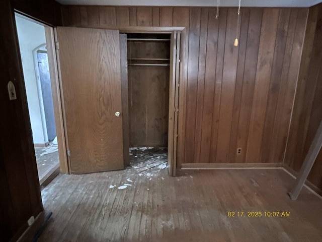 unfurnished bedroom featuring a closet, wooden walls, and hardwood / wood-style floors