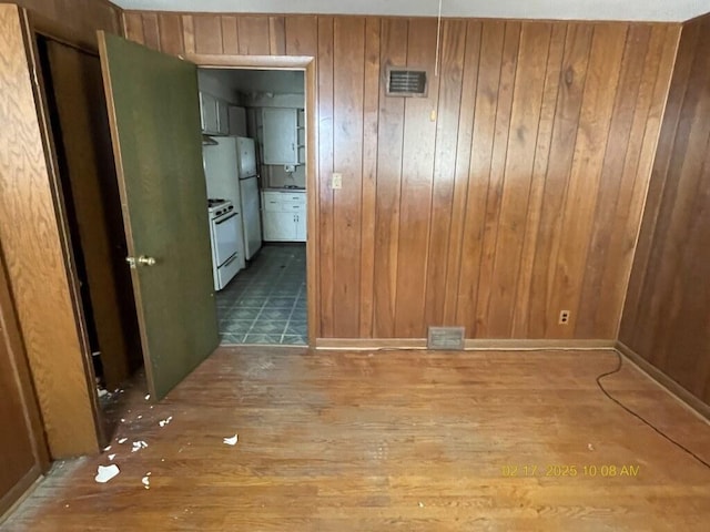 unfurnished room featuring wood finished floors, visible vents, and wooden walls