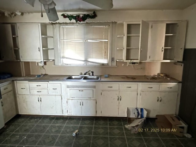 kitchen featuring dark countertops, white cabinetry, open shelves, and a sink