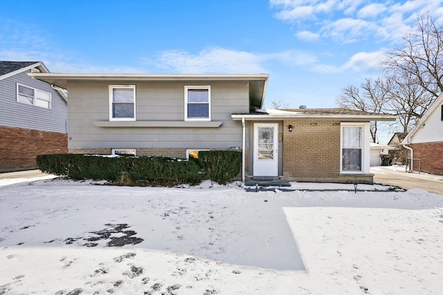 split level home featuring entry steps and brick siding