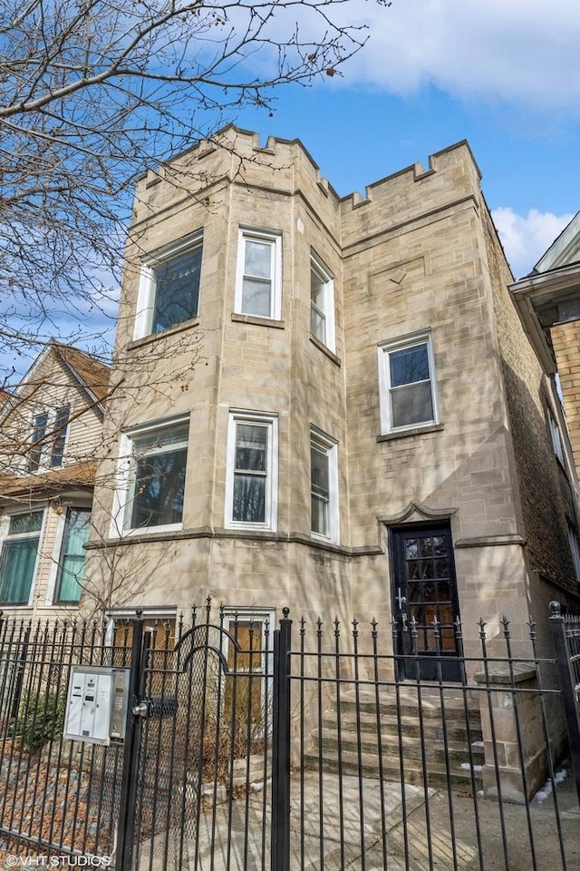 view of front of home featuring a gate, stone siding, and a fenced front yard