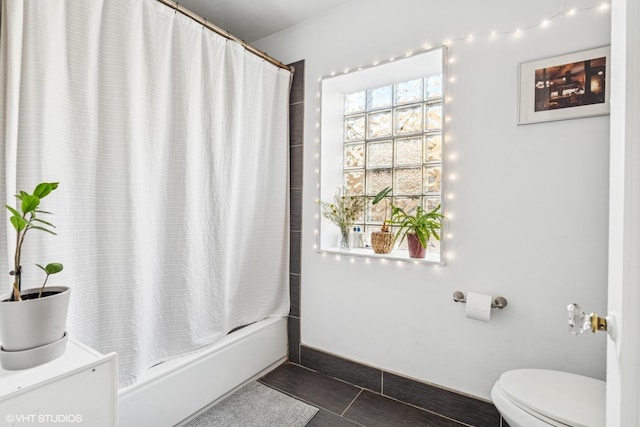 full bath with baseboards, shower / bath combo with shower curtain, and toilet