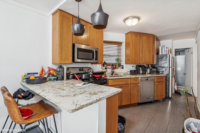 kitchen with a sink, stainless steel appliances, a peninsula, a breakfast bar area, and brown cabinetry