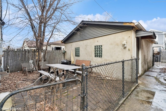 back of house featuring a gate, stucco siding, and fence