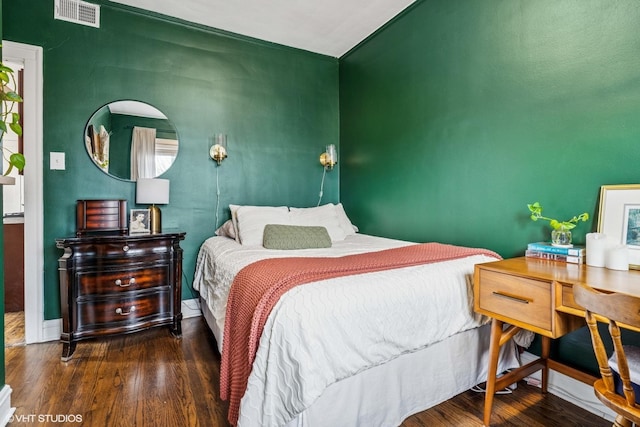 bedroom featuring visible vents, baseboards, and wood finished floors