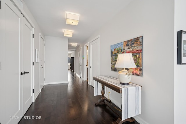 hallway featuring baseboards and dark wood-style flooring