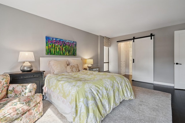 bedroom featuring wood finished floors, baseboards, and a barn door