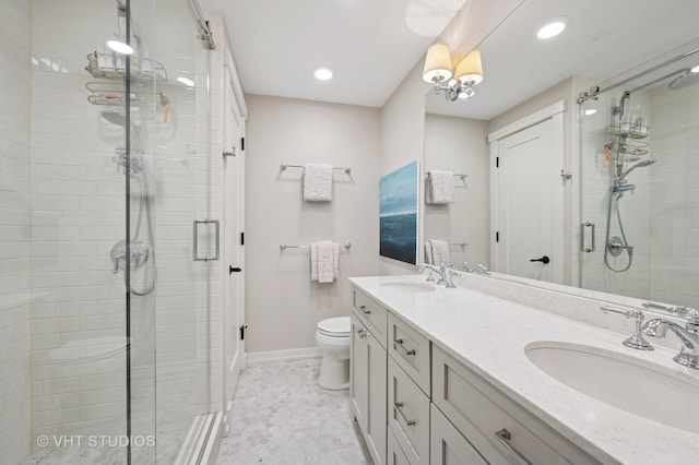 bathroom featuring toilet, a shower stall, double vanity, and a sink