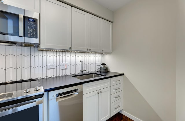 kitchen featuring appliances with stainless steel finishes, dark countertops, decorative backsplash, and white cabinets