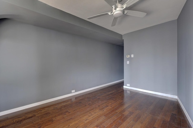 unfurnished room with dark wood-type flooring, a ceiling fan, and baseboards