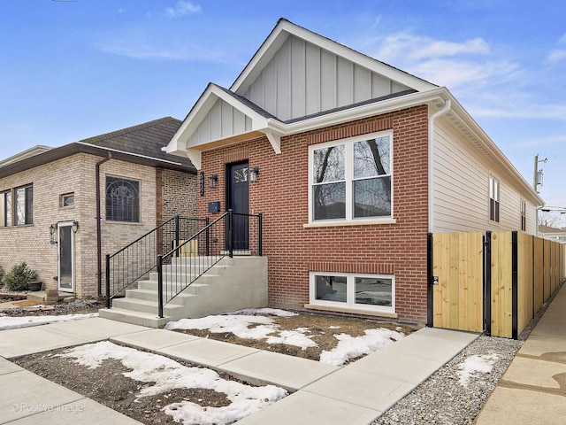 view of front of house featuring board and batten siding, a gate, and brick siding