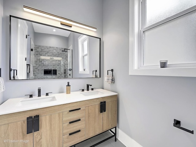 bathroom with double vanity, a stall shower, a sink, and baseboards