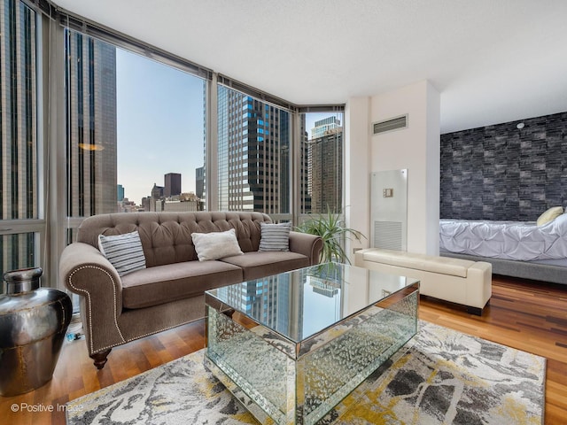 living area with a wall of windows, visible vents, a view of city, and wood finished floors