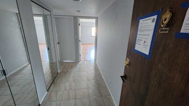 corridor with baseboards and light tile patterned flooring