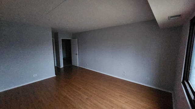 empty room with visible vents, wood finished floors, and baseboards