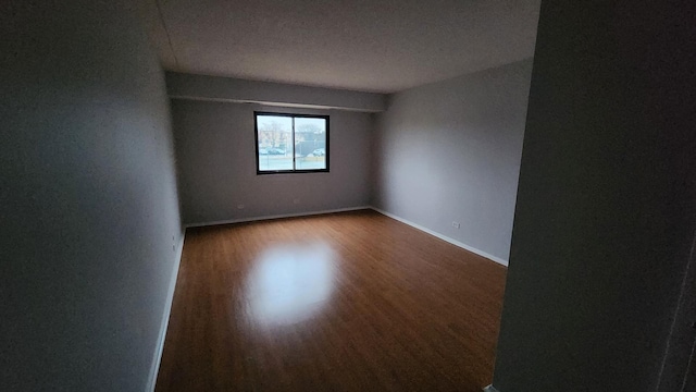 spare room featuring baseboards and wood finished floors