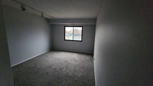 carpeted empty room featuring baseboards and track lighting