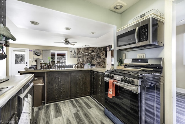 kitchen featuring ceiling fan, appliances with stainless steel finishes, wood finished floors, light countertops, and dark brown cabinets