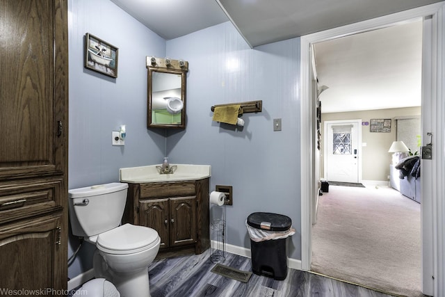 half bathroom with toilet, baseboards, wood finished floors, and vanity