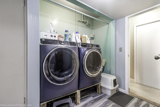 laundry room featuring laundry area, wood finished floors, washing machine and clothes dryer, and baseboards