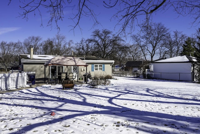 snow covered house featuring fence