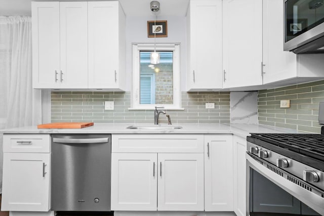 kitchen with stainless steel appliances, light countertops, a sink, and white cabinetry