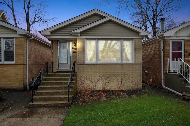 bungalow featuring entry steps, a front lawn, and brick siding