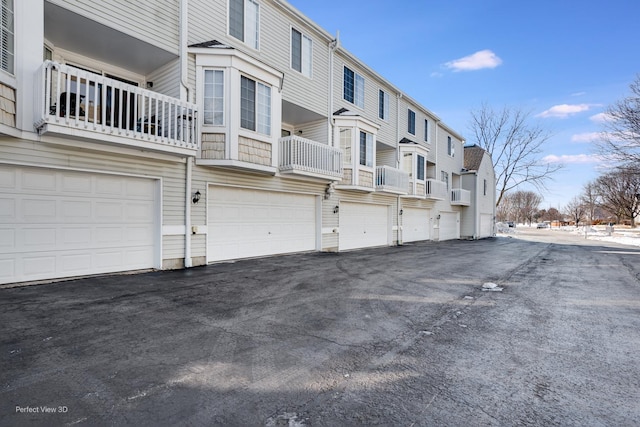 exterior space with driveway, an attached garage, cooling unit, and a residential view