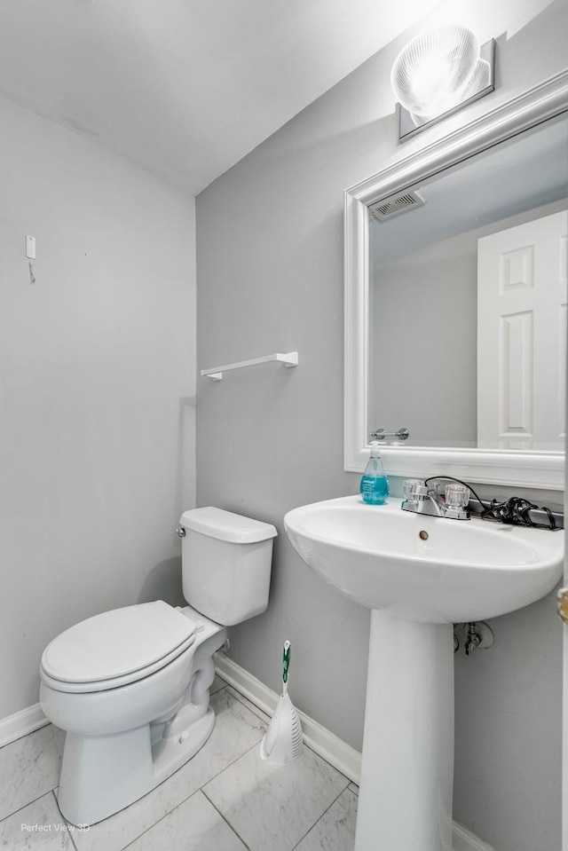 half bathroom with toilet, marble finish floor, visible vents, and baseboards