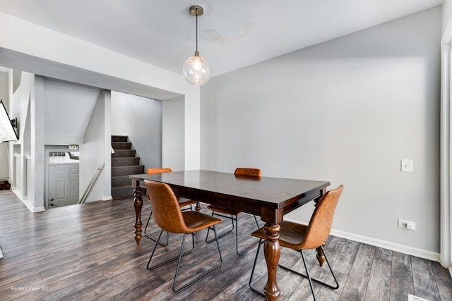 dining area featuring dark wood-type flooring, stairway, and baseboards