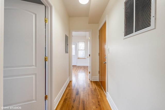 hall with light wood finished floors, visible vents, and baseboards