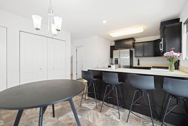 kitchen with light countertops, stainless steel refrigerator with ice dispenser, a kitchen breakfast bar, and a peninsula