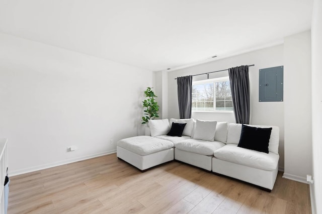 living room with light wood-type flooring, electric panel, and baseboards