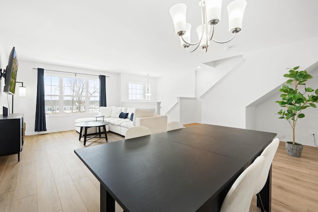 dining area featuring light wood finished floors, baseboards, stairway, and a notable chandelier