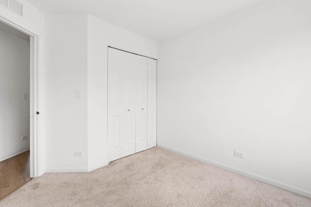 unfurnished bedroom with baseboards, carpet, visible vents, and a closet