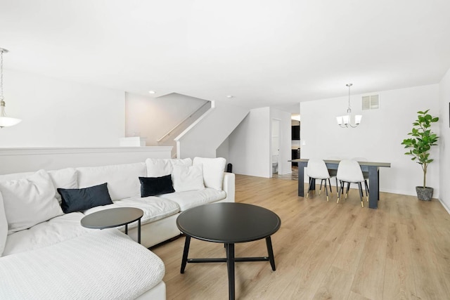 living area with light wood-type flooring, visible vents, and a notable chandelier