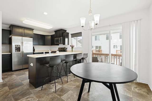 kitchen with appliances with stainless steel finishes, a kitchen breakfast bar, a peninsula, light countertops, and a chandelier