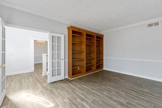 unfurnished room with french doors, visible vents, crown molding, and wood finished floors