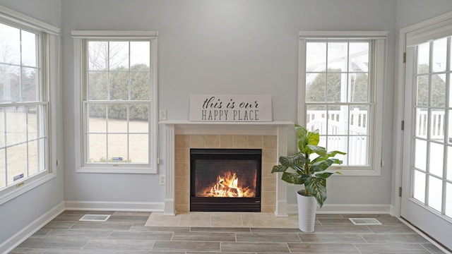 interior space with a healthy amount of sunlight, visible vents, a fireplace, and baseboards