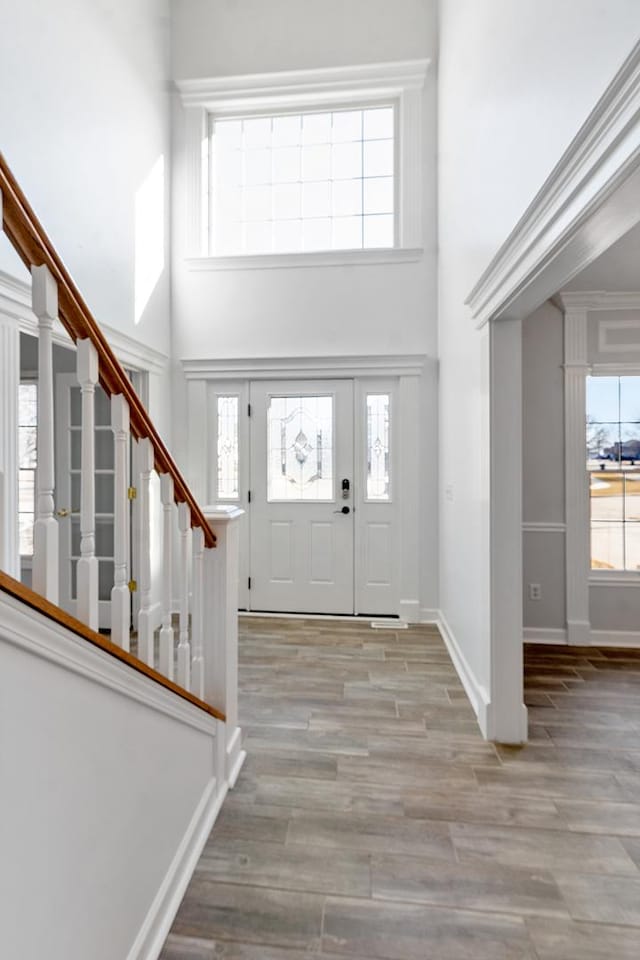 entrance foyer featuring baseboards, a high ceiling, stairway, and wood finished floors