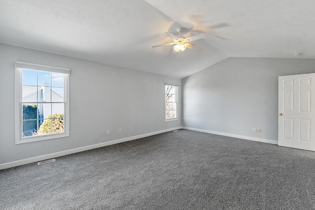 unfurnished room with baseboards, visible vents, lofted ceiling, ceiling fan, and dark carpet