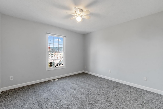 carpeted spare room with a ceiling fan, visible vents, and baseboards