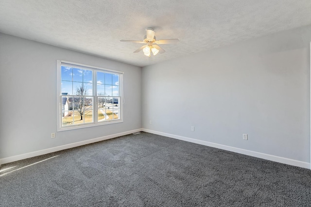 unfurnished room with ceiling fan, baseboards, dark colored carpet, and a textured ceiling