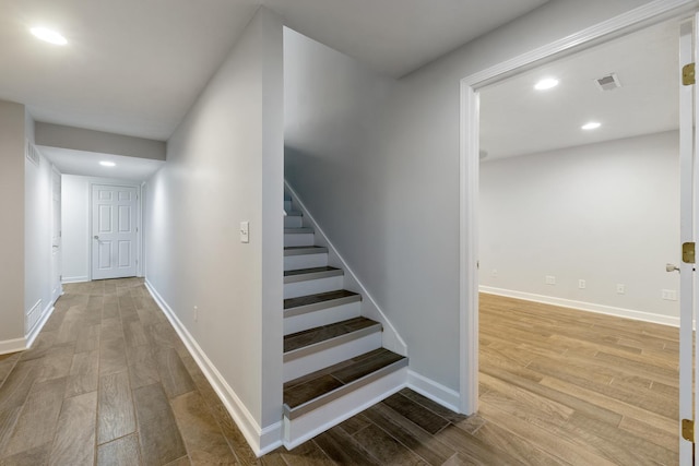 staircase with baseboards, wood finished floors, and recessed lighting