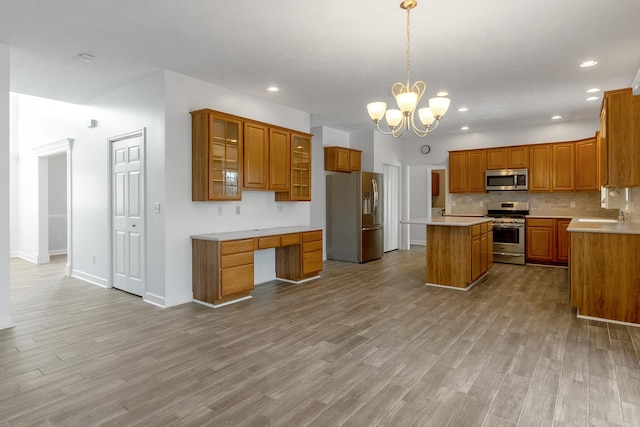 kitchen featuring a center island, brown cabinets, decorative backsplash, appliances with stainless steel finishes, and wood finished floors